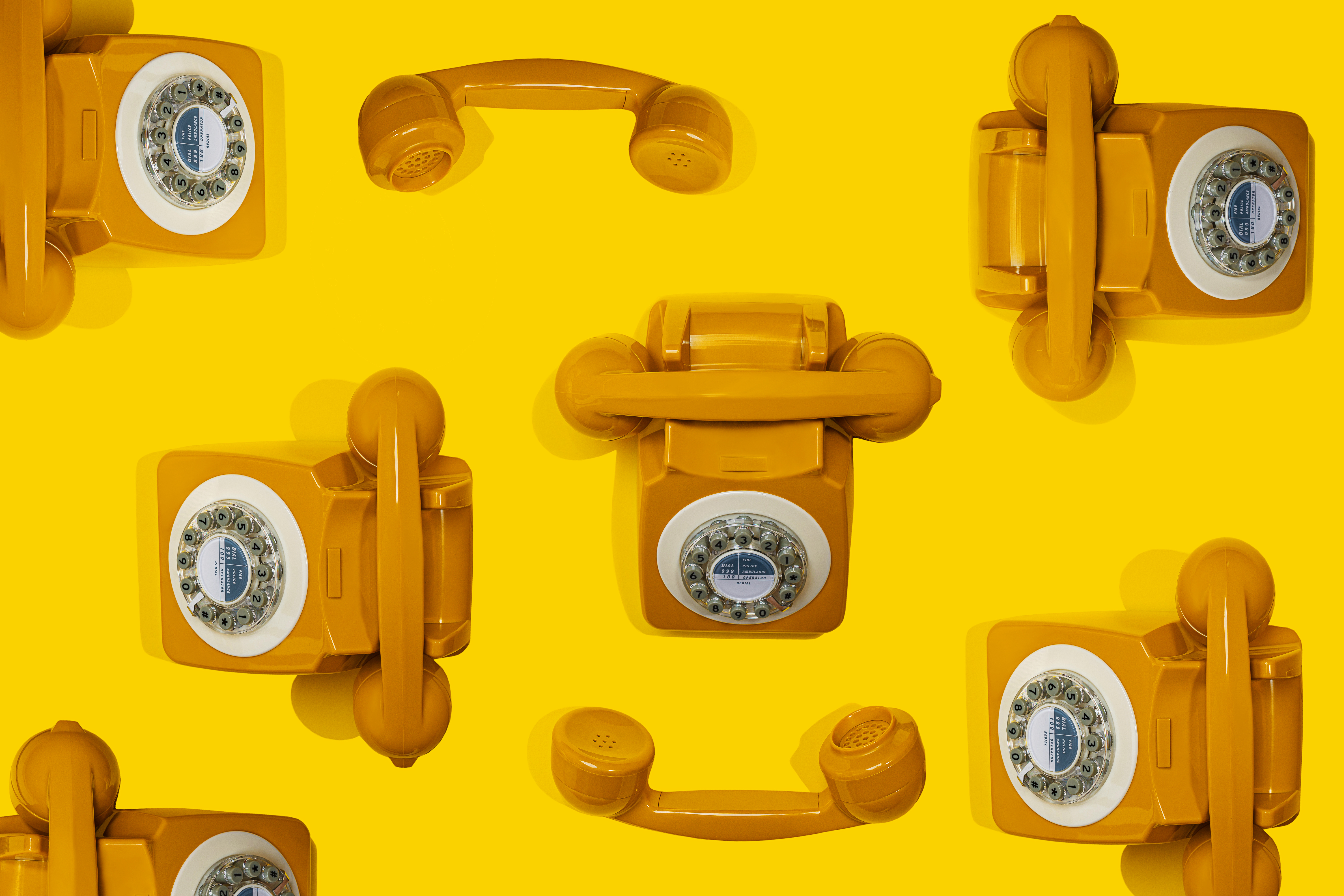 Image of vintage yellow phones on a yellow background.