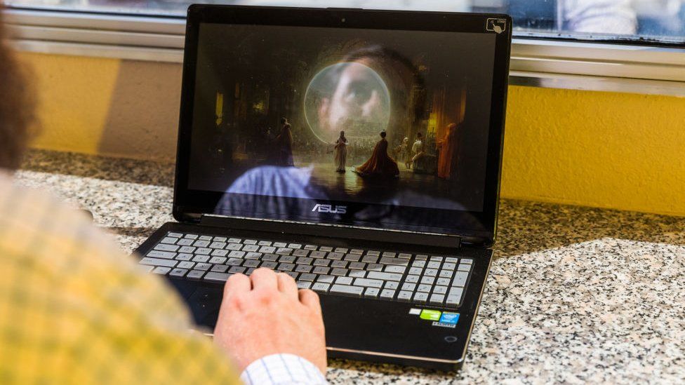 Jason Allen with a picture of his artwork on a laptop