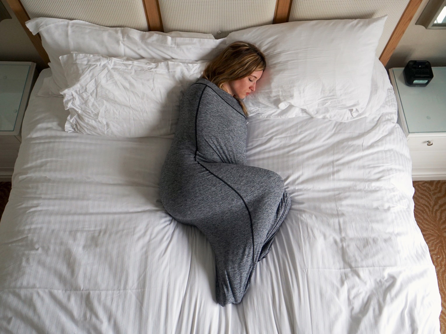 Person lying on bed wrapped in the Sleep Pod blanket