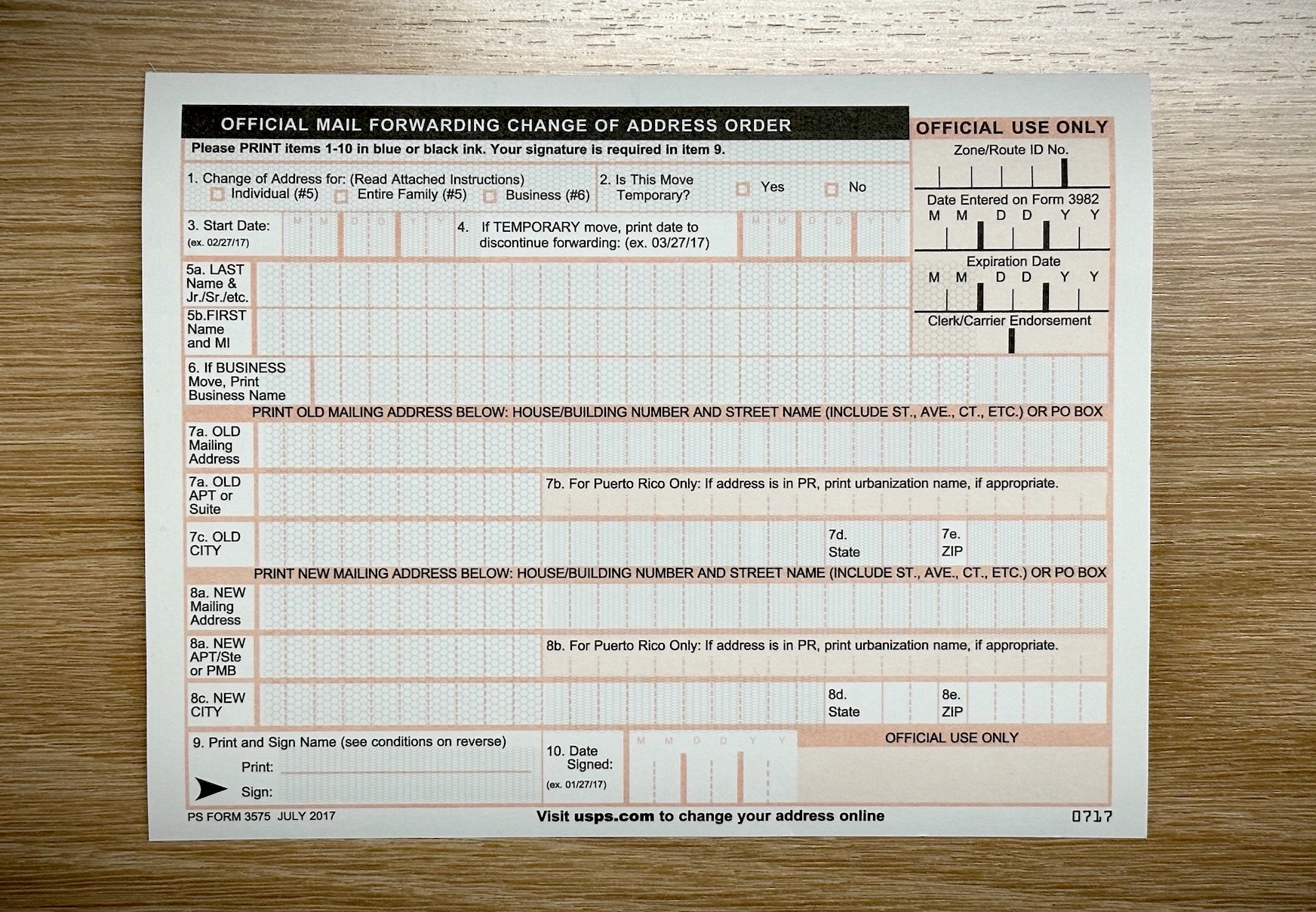 a postcard-sized change of address form, made of paper, facing front-side up on a flat wooden desk.