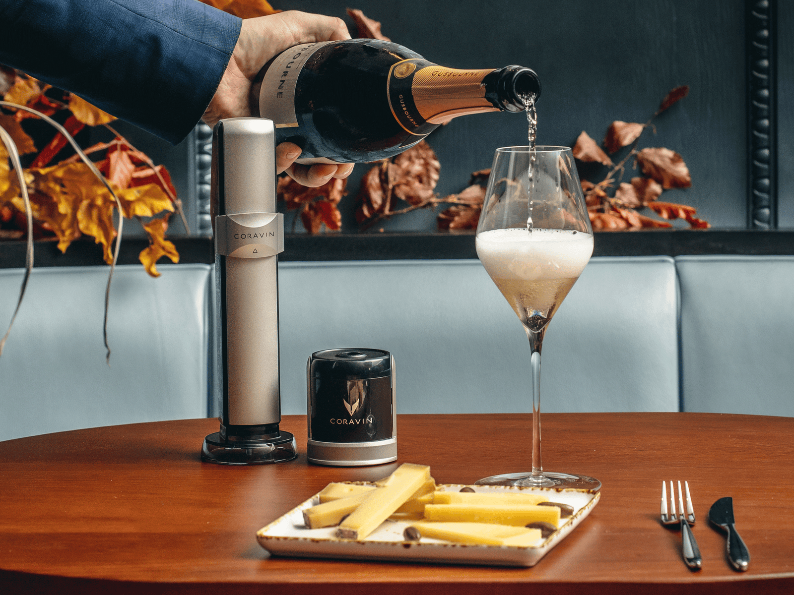 Person's hand pouring a glass on sparking line next to the Coravin Sparkling wine preservation system