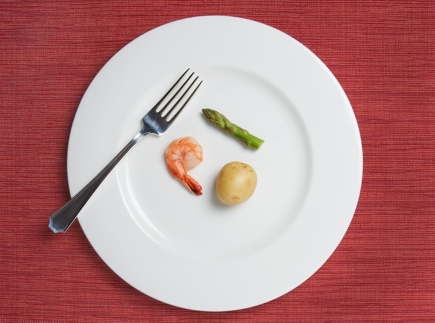 tiny meal consisting of one shrimp, a tiny potato, and a single short asparagus stalk