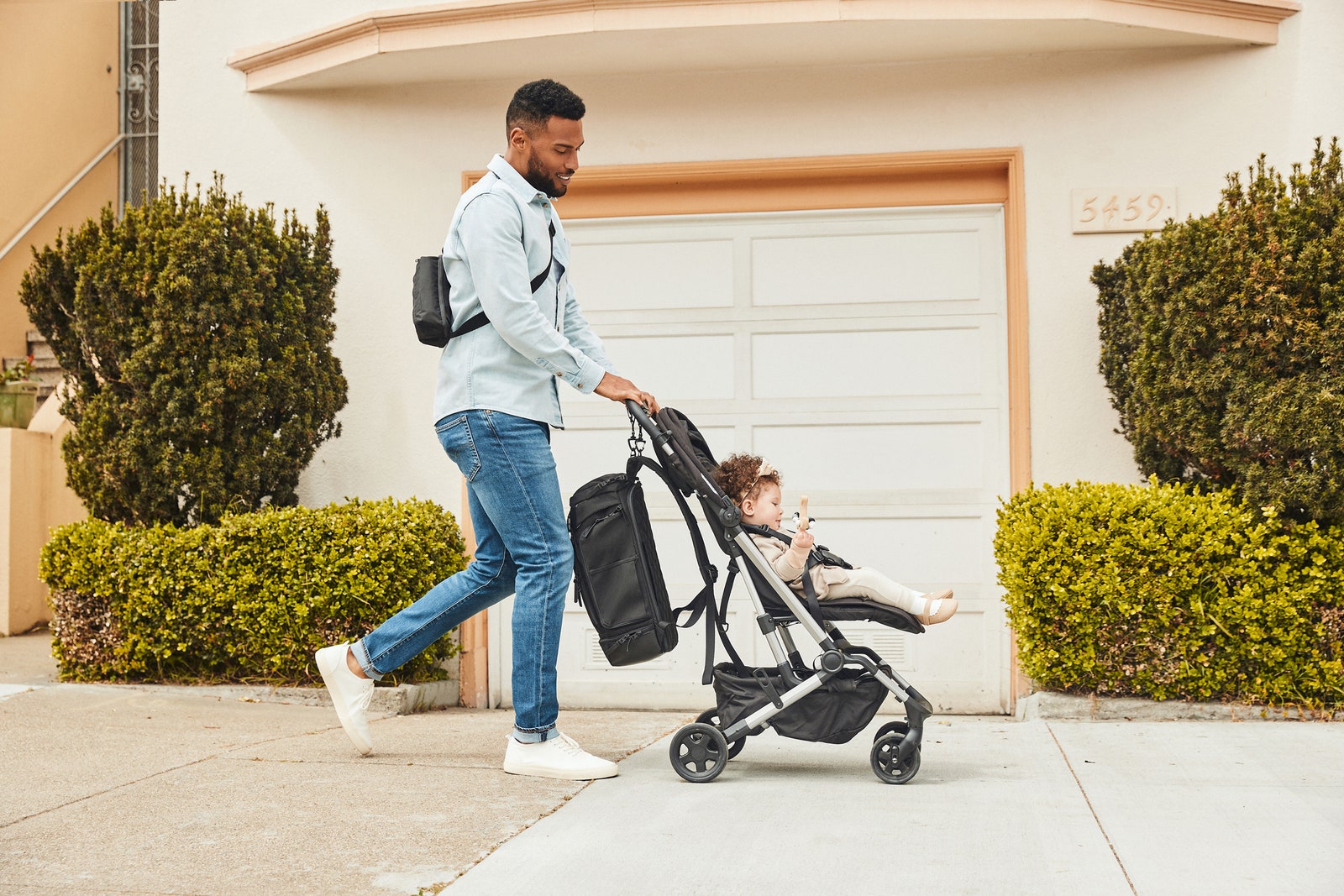 Person pushing a stroller and wearing the No Reception Club Getaway Bag