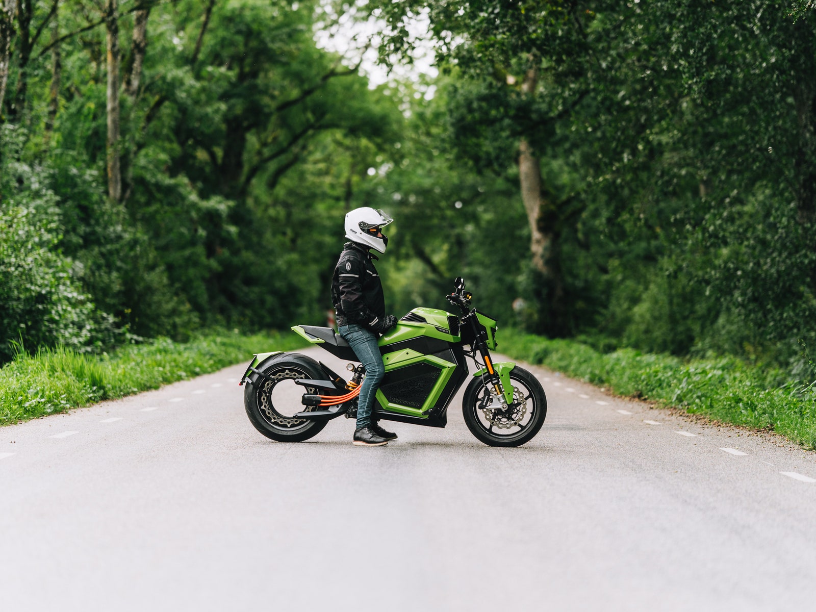 Person sitting on the Verge TS Pro electric motorcycle in an empty roadway