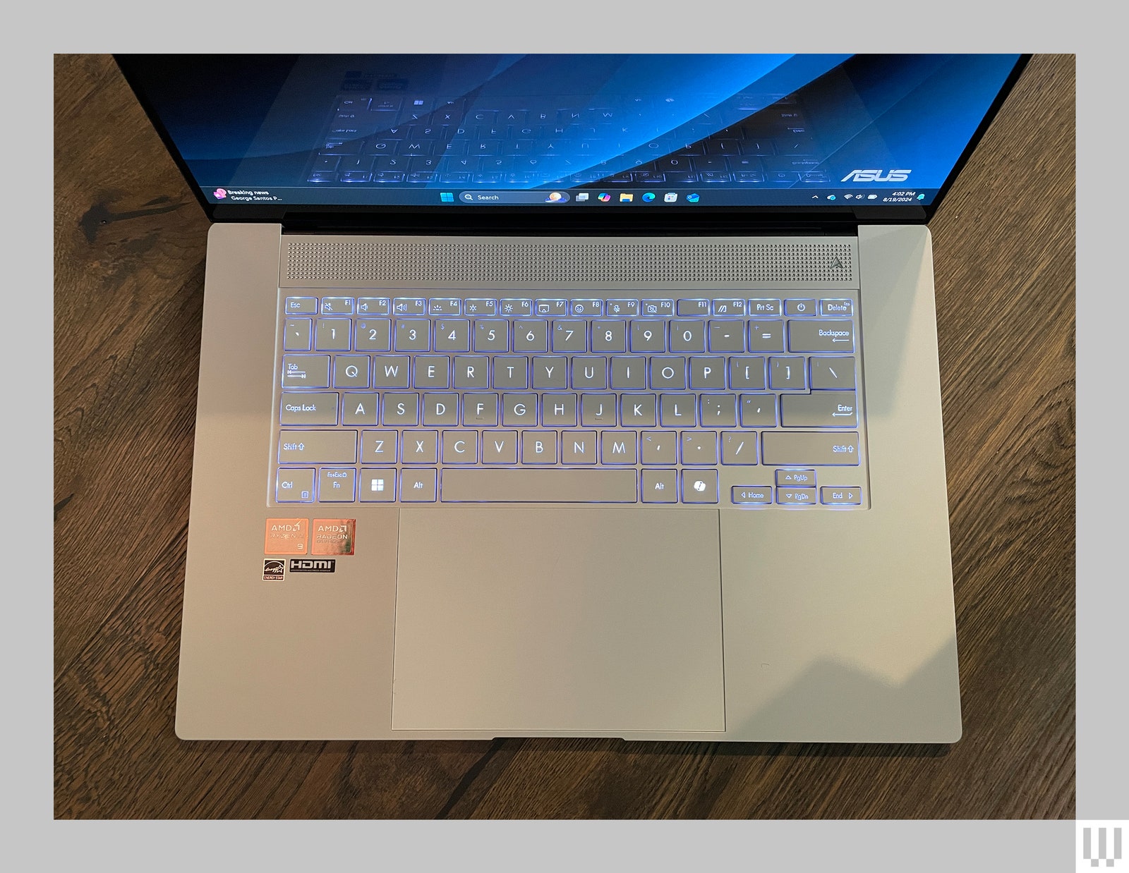 Overhead view of illuminated keyboard of a laptop sitting on a hardwood floor