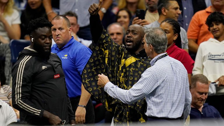 A fan, at center, gets removed from his seat after attempting to get a haircut during the quarterfinals of the U.S. Open tennis championships between Nick Kyrgios, of Australia, and Karen Khachanov, of Russia, Tuesday, Sept. 6, 2022, in New York. (AP Photo/Charles Krupa)