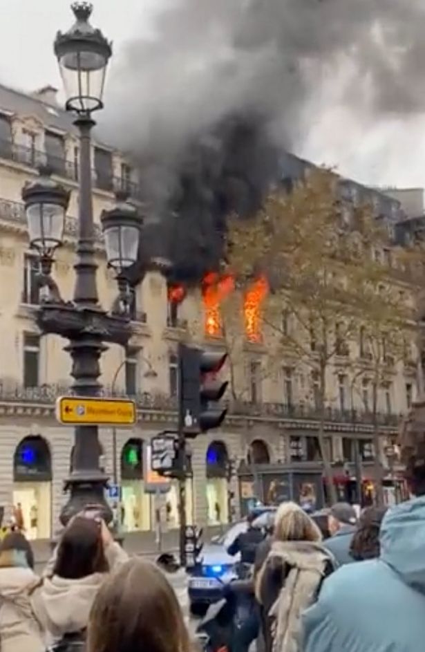 Black smoke can be seen coming out from two windows, with flames visible from the street