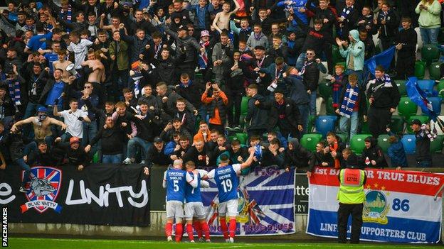 Linfield scored twice in the final three minutes of the first half to spark wild celebrations at Windsor Park