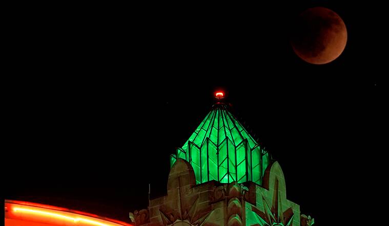 Lunar eclipse vcovering the moon as it rises beyond buildings in Kansas