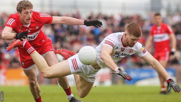 Cathal McShane is unable to win possession as he is challenged by Brendan Rogers at Healy Park