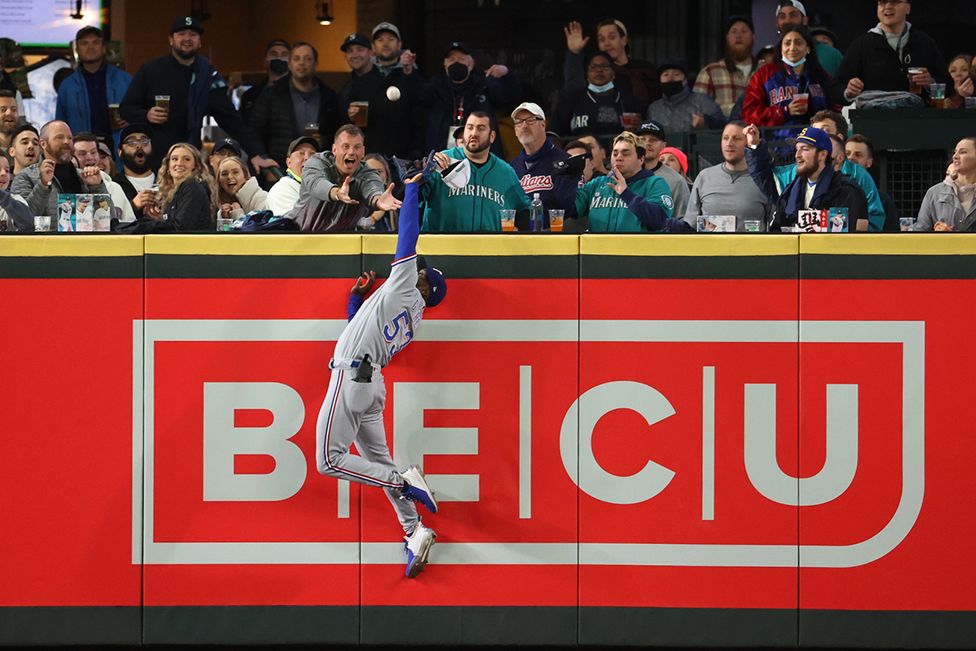 Adolis Garcia of the Texas Rangers takes a home run away from Mitch Haniger of the Seattle Mariners