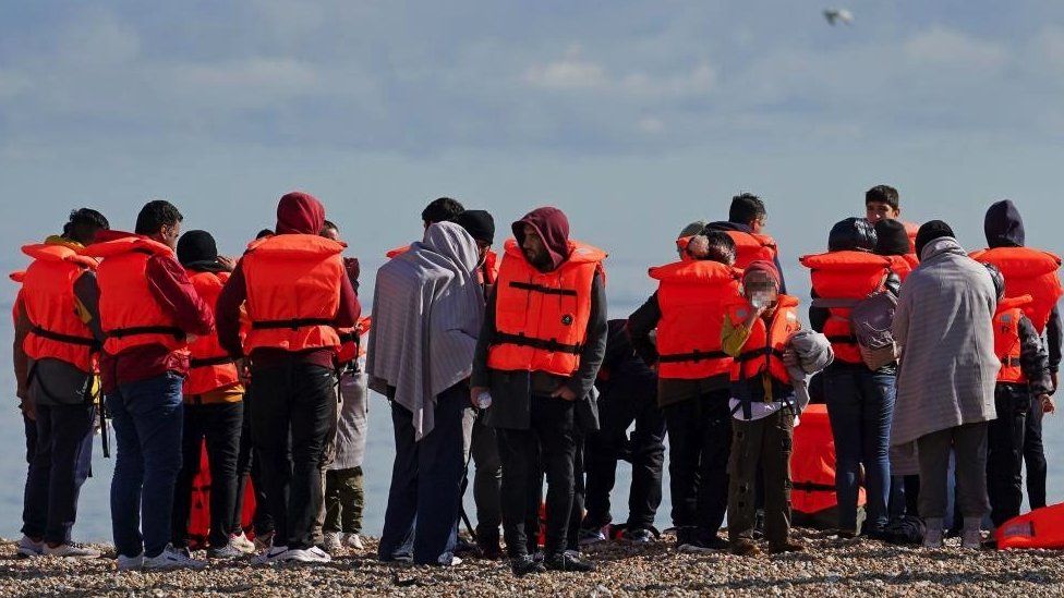 A group of people thought to be migrants on the beach in Dungeness, Kent, after being rescued in the Channel by the RNLI following following a small boat incident