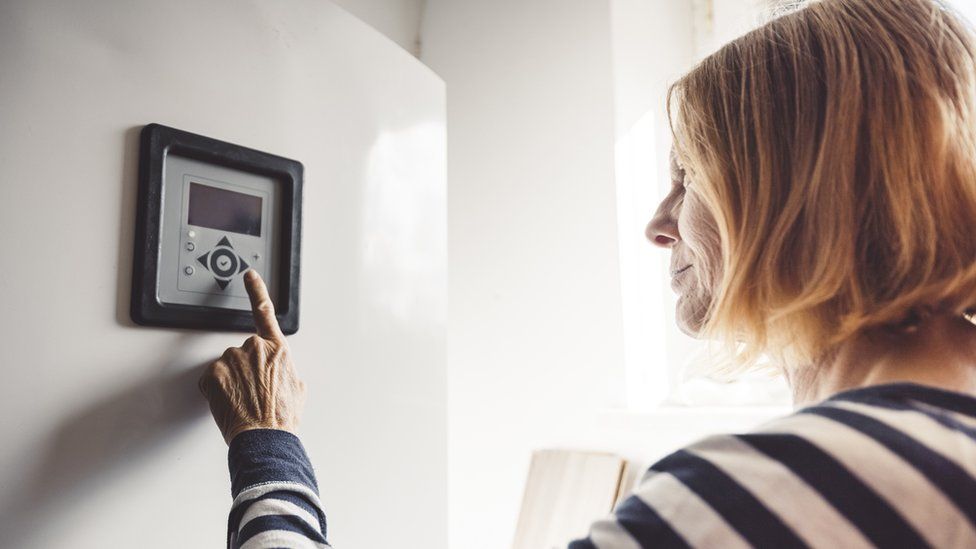 Woman checking heating thermostat