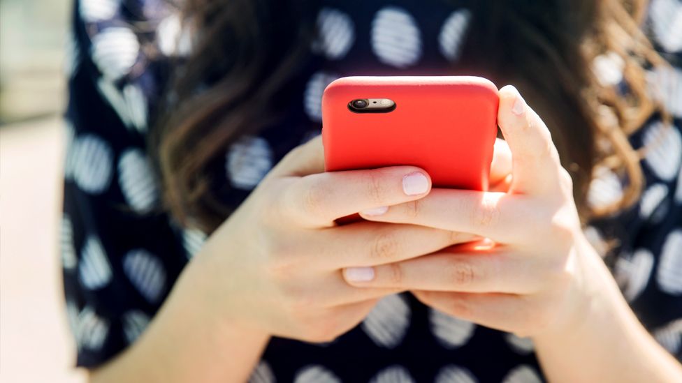 A woman holds a mobile phone