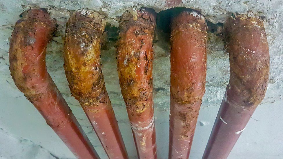 Old lead pipes emerging from a concrete wall