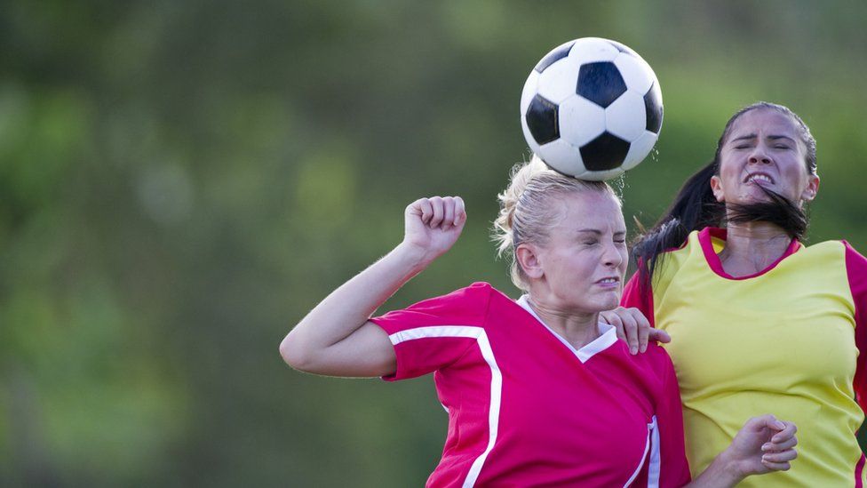 women footballers heading the ball