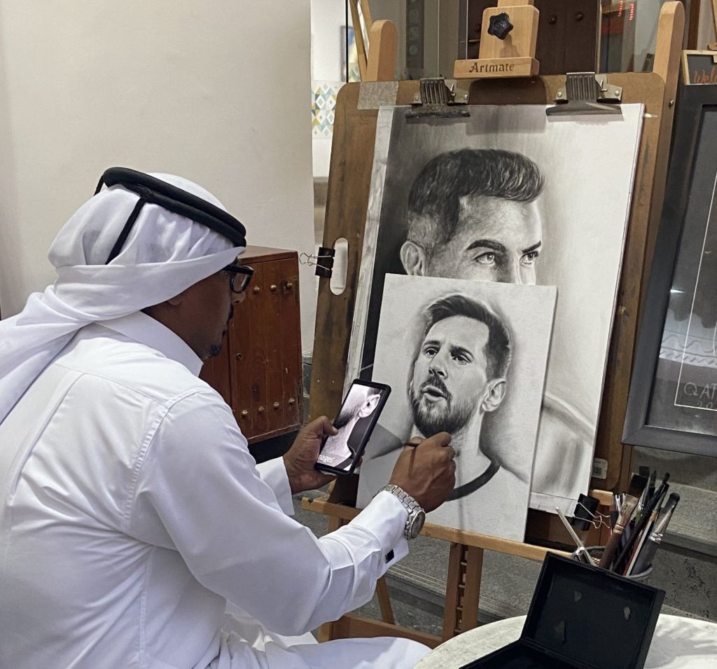 A Qatari artist works on a charcoal portrait Argentine striker Lionel Messi