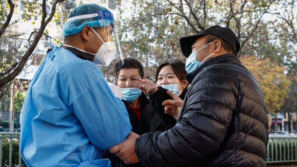 A woman (2-R) argues with a volunteer health worker (L) at a COVID-19 test site in Beijing, China, 21 November 2022