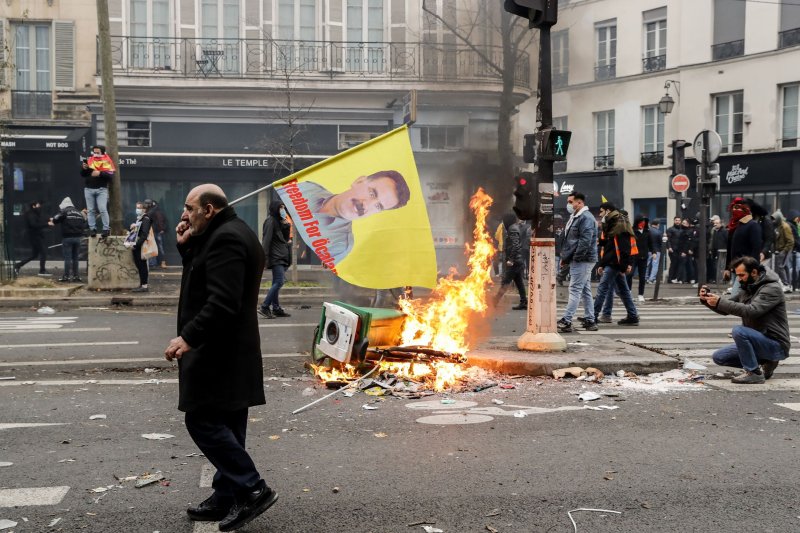 A protestor walks past burning debris following clashes with police in Paris Saturday, a day after three people were killed and others seriously injured after a gunman opened fire outside a Kurdish cultural center. Photo by Teresa Suarez/EPA-EFE