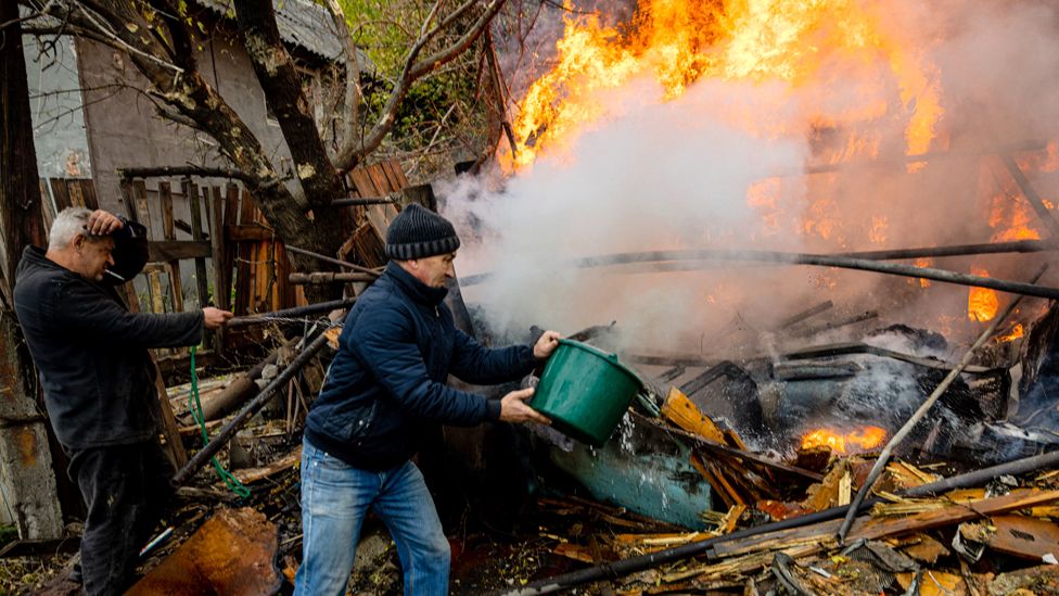 Local residents work to extinguish a fire after shelling in the town of Bakhmut, in eastern Ukraine's Donbas region, on 23 October 2022