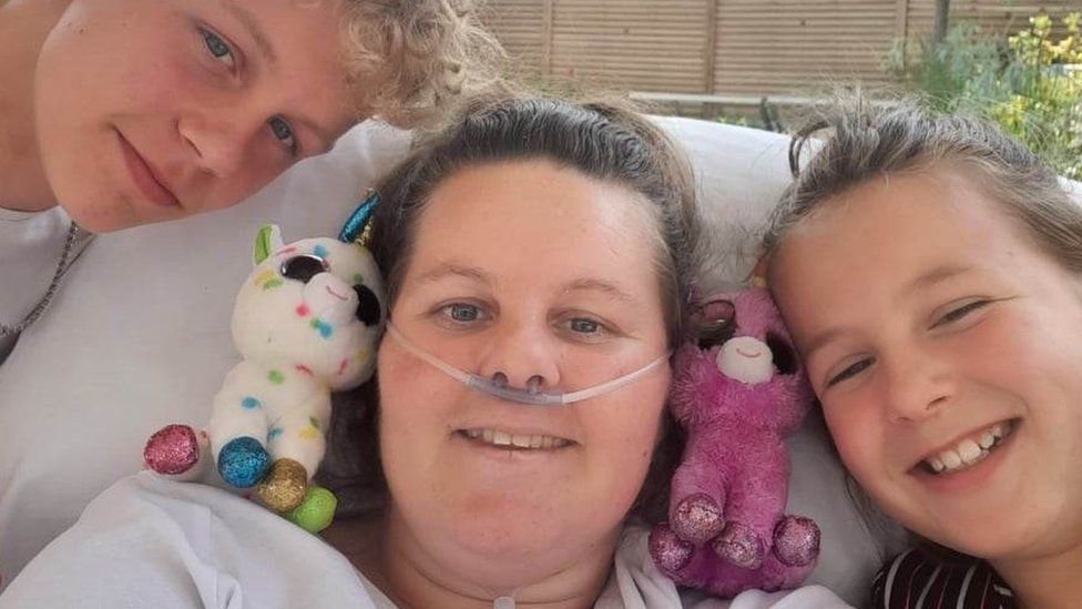 Louise Evans in bed at Stoke Mandeville Hospital with her two children visiting