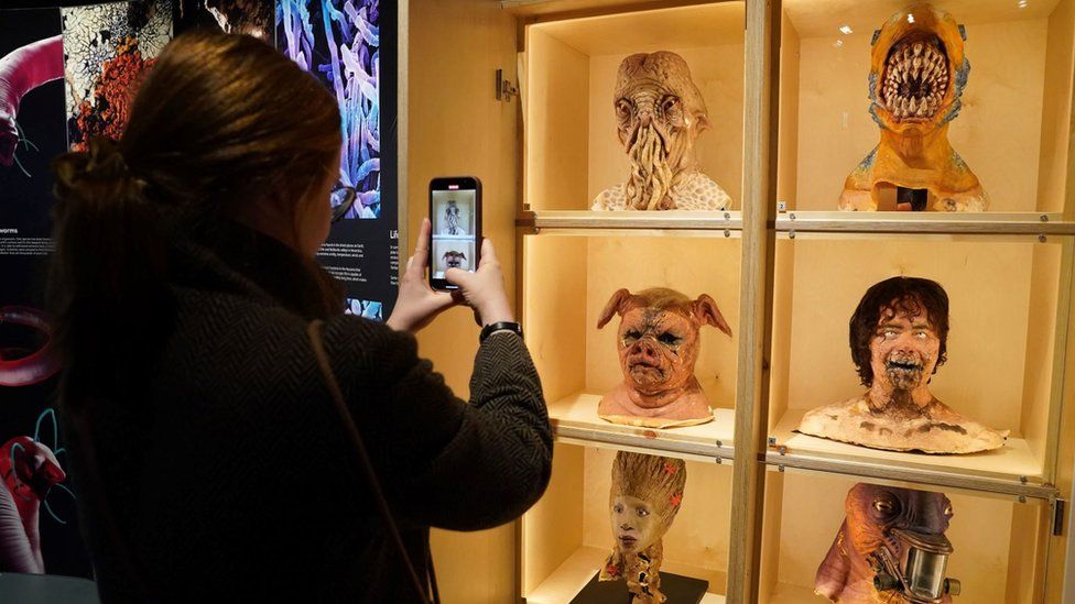 A visitor takes photos of masks from Doctor Who