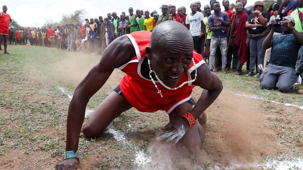 A Maasai Moran falls after throwing a javelin