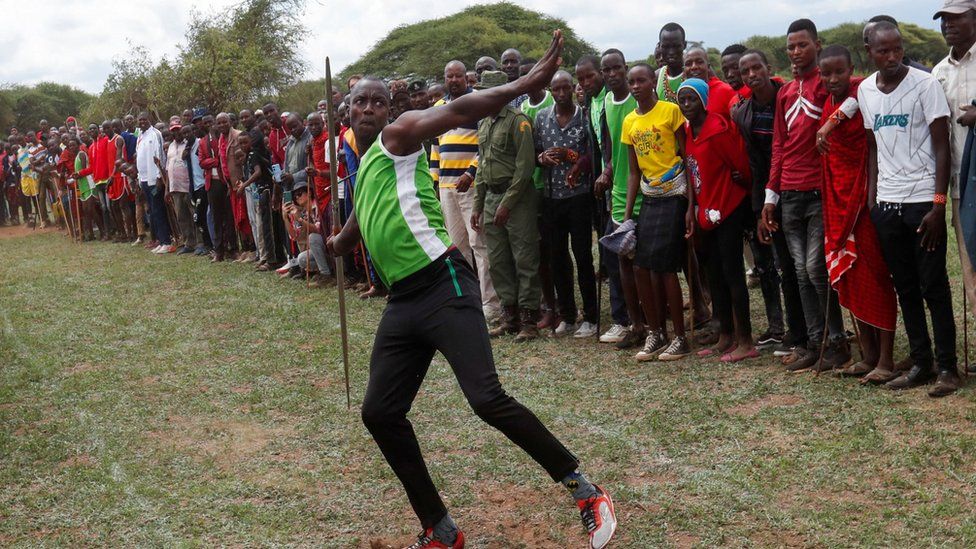 Spectators watch as a Maasai Moran throws a javelin
