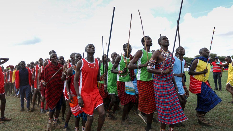 Maasai warriors in their traditional attire sing as they warm up before the start of the games