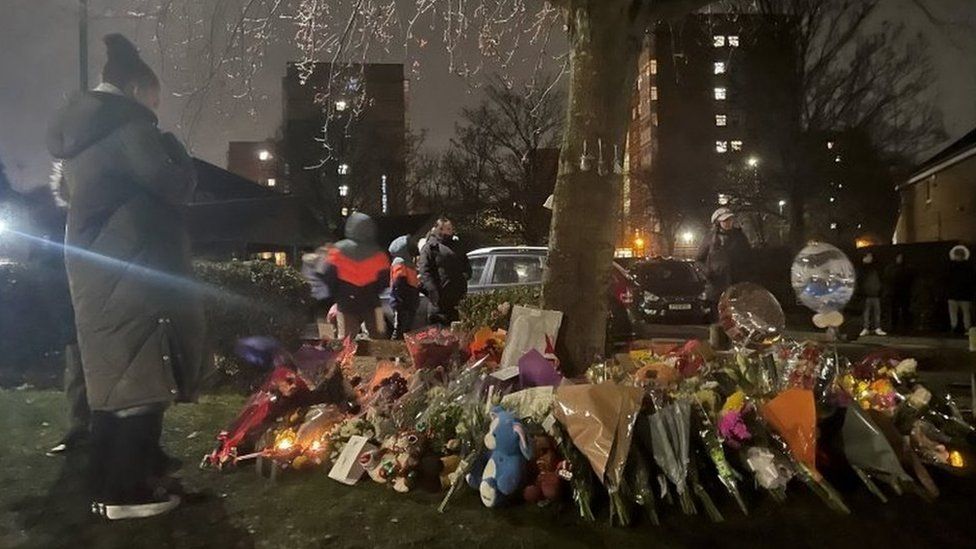 Floral tributes and balloons near the lake