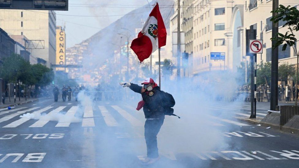 A supporter of former Peruvian President Pedro Castillo wears a mask to protect himself from tear gas during a protest near Congress in Lima