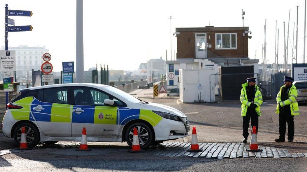 Police stand next to police car in Dover