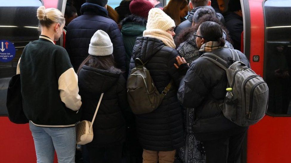 Commuters board an extremely delayed Central Line train at Stratford station in London on a strike day.