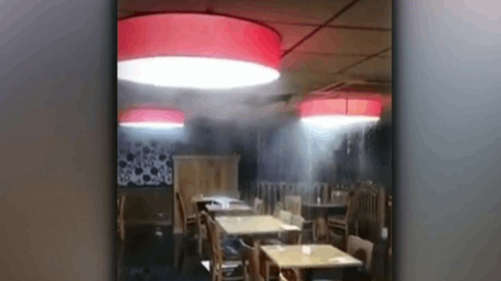 Water seen pouring from the ceiling into the restaurant and over furniture