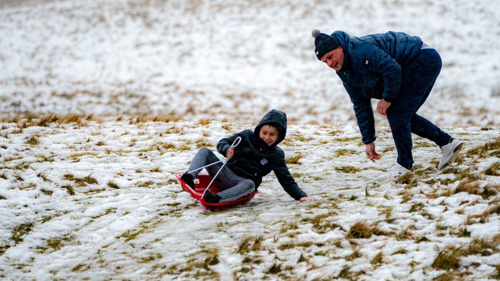 A sledger makes the most of the snow on an icy and snowy hill as rain falls in the Brecon Beacons National Park, Wales. Snow and ice have swept across parts of the UK,