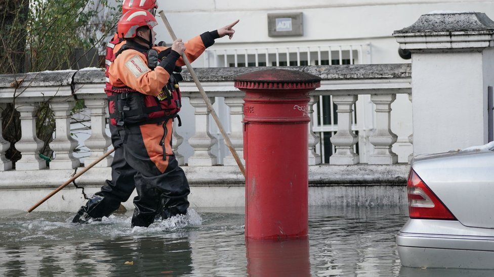 Fire crews wading through flood water