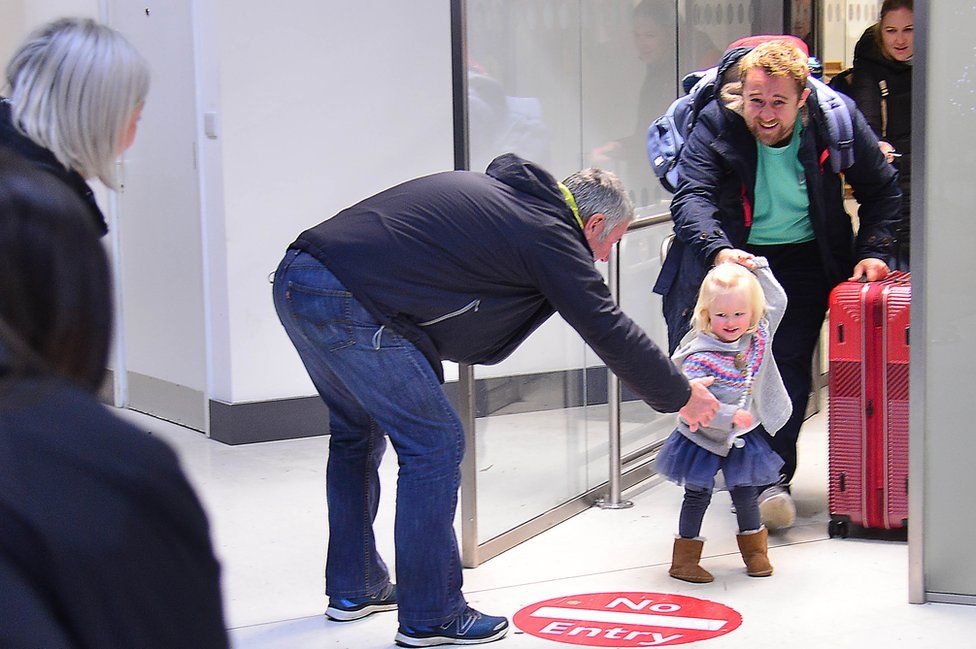 A young girl runs to her grandfather after arriving at Belfast City Airport