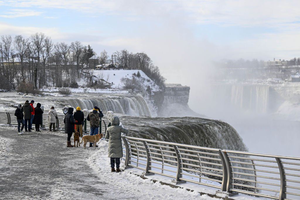 Tourists standing by fence, overlooking falls