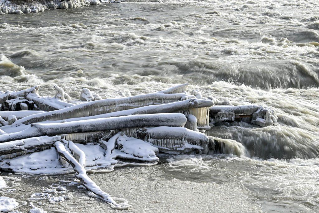 Close of wooden logs connected by large icicles