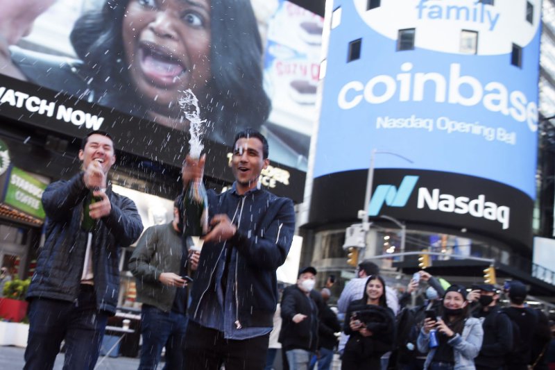 Employees and supporters of Coinbase pop the corks on bottles of champagne at the Nasdaq MarketSite where the Coinbase logo is displayed in New York City on April 14, 2021. Coinbase agreed to pay a New York regulator $50 million on Wednesday. File Photo by John Angelillo/UPI | <a href="/News_Photos/lp/f65adb56d6558dc60874493381ac17e2/" target="_blank">License Photo</a>