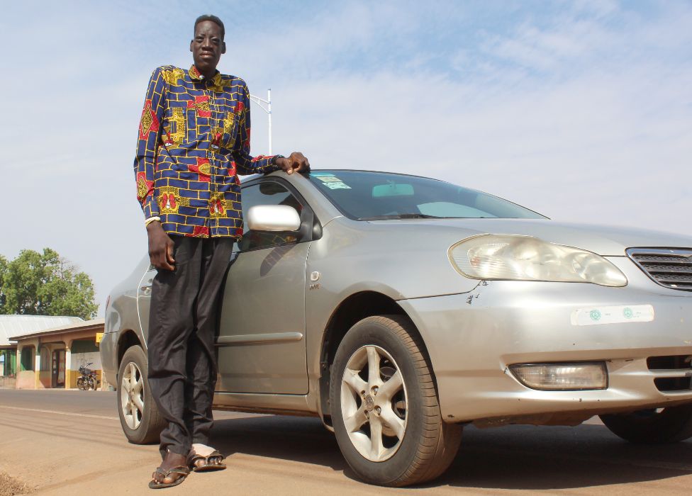 Awuche next to a car