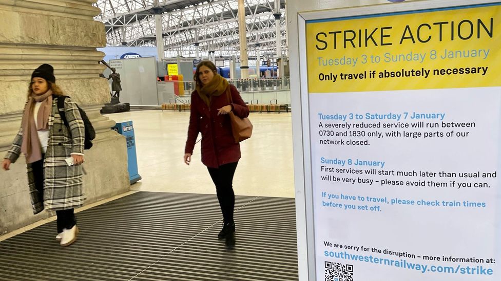 Women and a sign at a train station