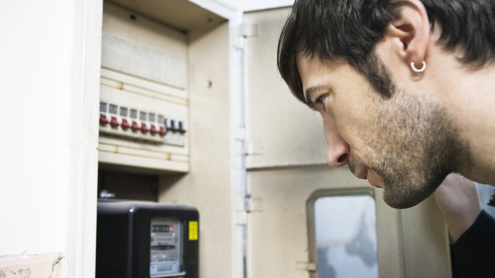 Man looking at electricity meter