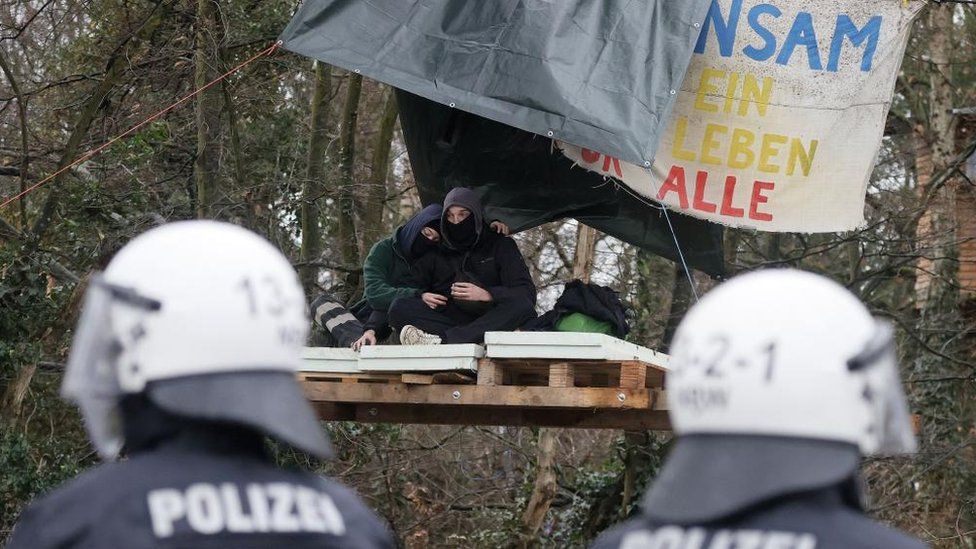 Activists sit on pallets hung in a tree at the village of Luetzerath, Germany, 11 January 2023