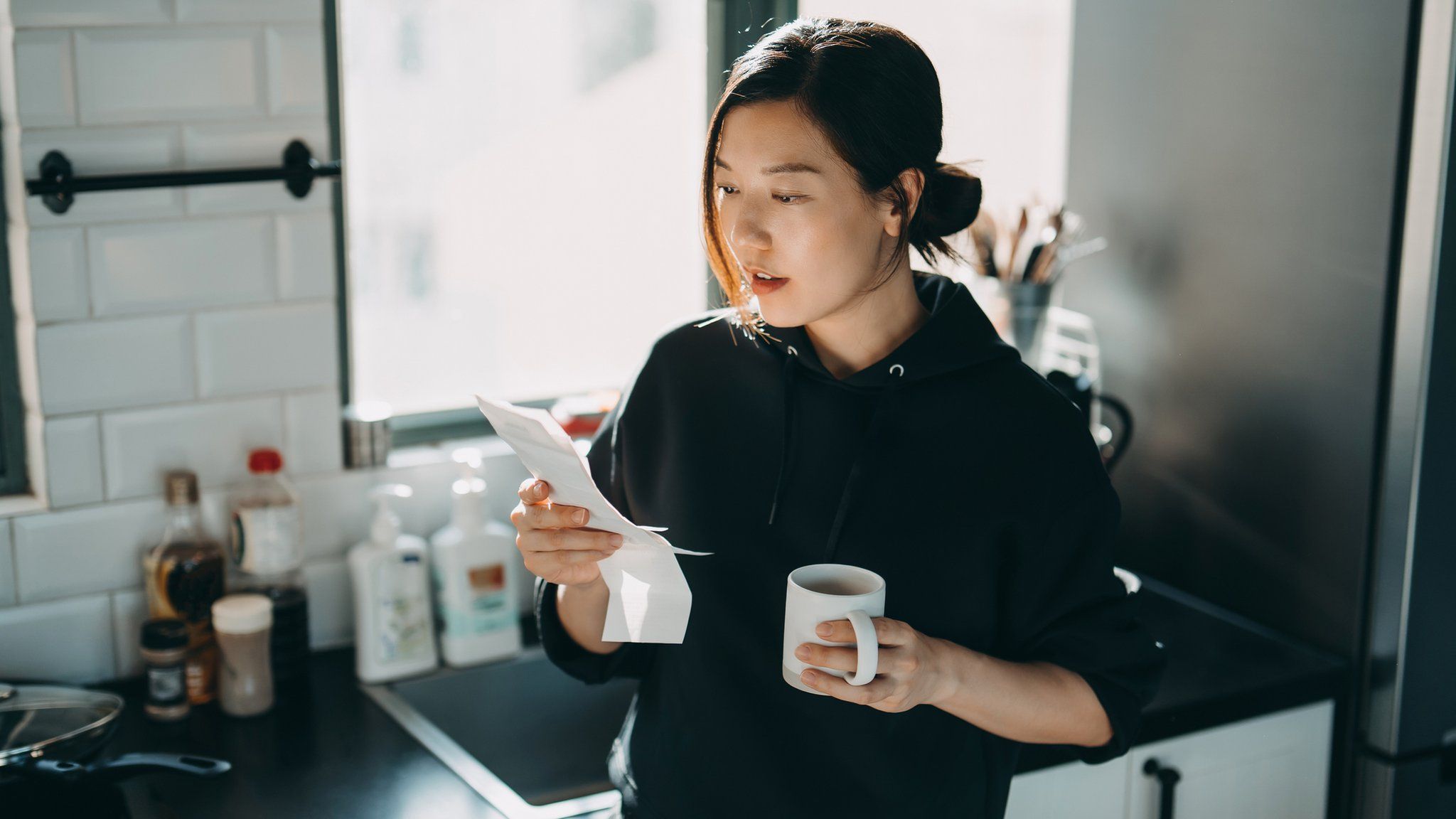 Woman looking at energy bill while having a cup of tea