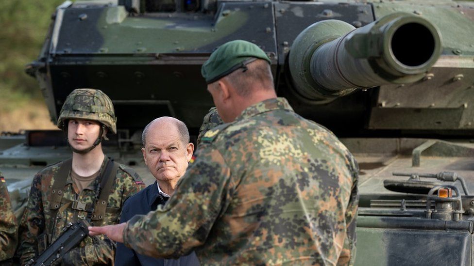 German Chancellor Olaf Scholz walks past a Leopard 2 main battle tank of the Bundeswehr while visiting the Bundeswehr army training center in Ostenholz on October 17, 2022 near Hodenhagen, German