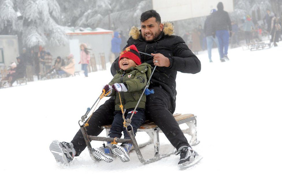 A man and a boy ride a sledge in the snow.