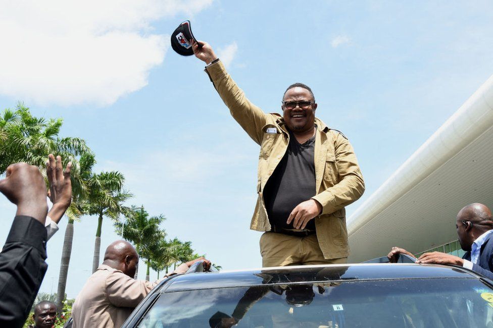 Tundu Lissu waves from a car top.