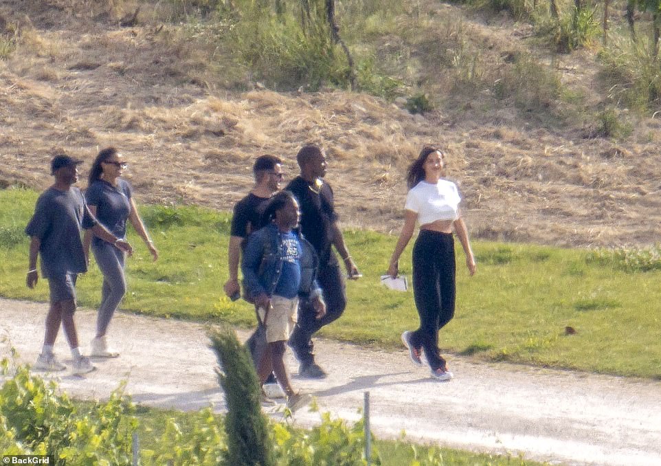 Part of the family: Irina can be seen smiling as she takes a stroll with Kanye and his team while on a romantic trip to France