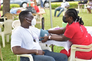 An official prepares to take blood from a donor